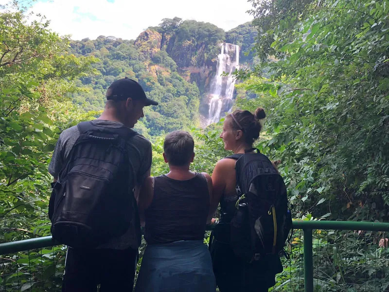 Hikers looking at a waterfall from a forest viewpoint on a Kilimanjaro climbing tour by the Machame Route, Tanzania