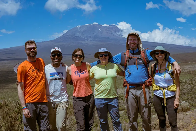 Group of hikers with the snow-capped Kibo summit behind them on a Kilimanjaro climbing tour by the Lemosho Route, Tanzania