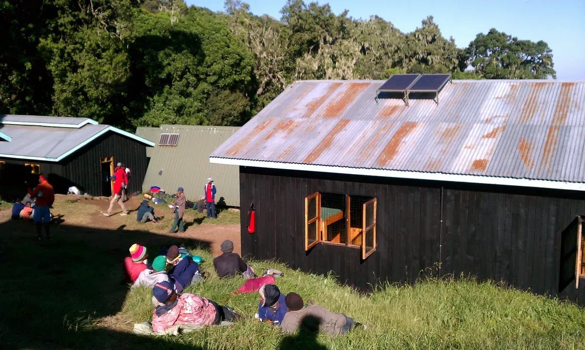 Trekkers resting on the grass at Mandara Hut, a sight on Kilimanjaro climbing tours