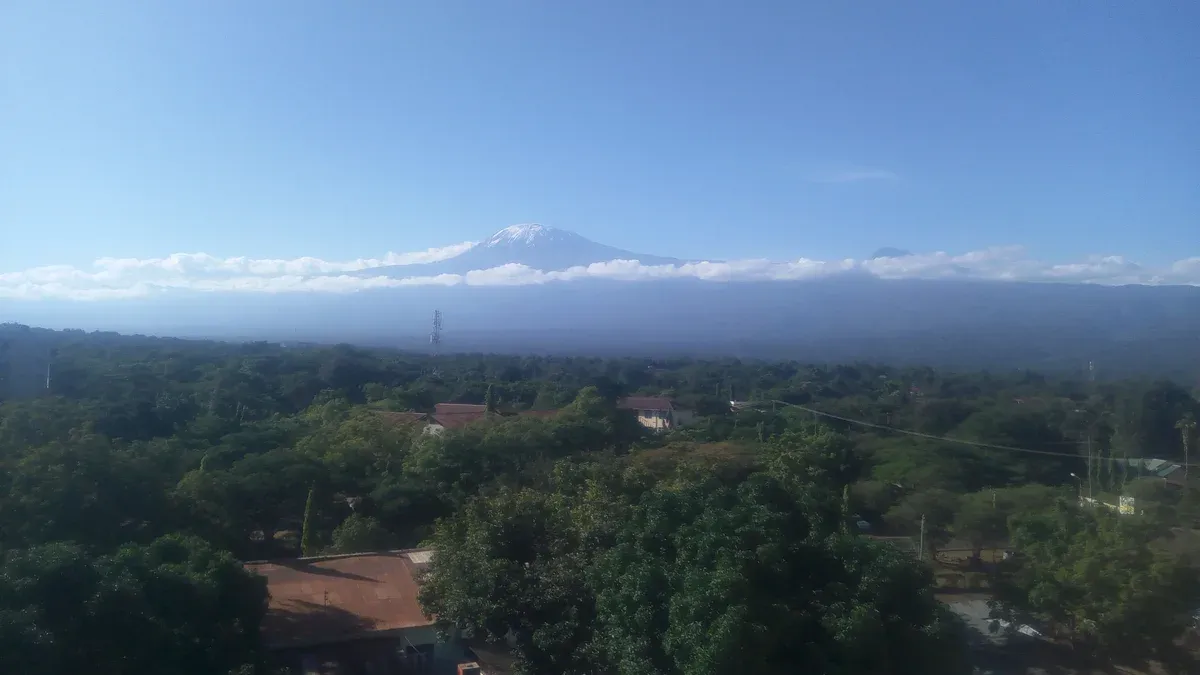 Kibo above the green rooftops of Moshi town, a sight on Kilimanjaro climbing tours